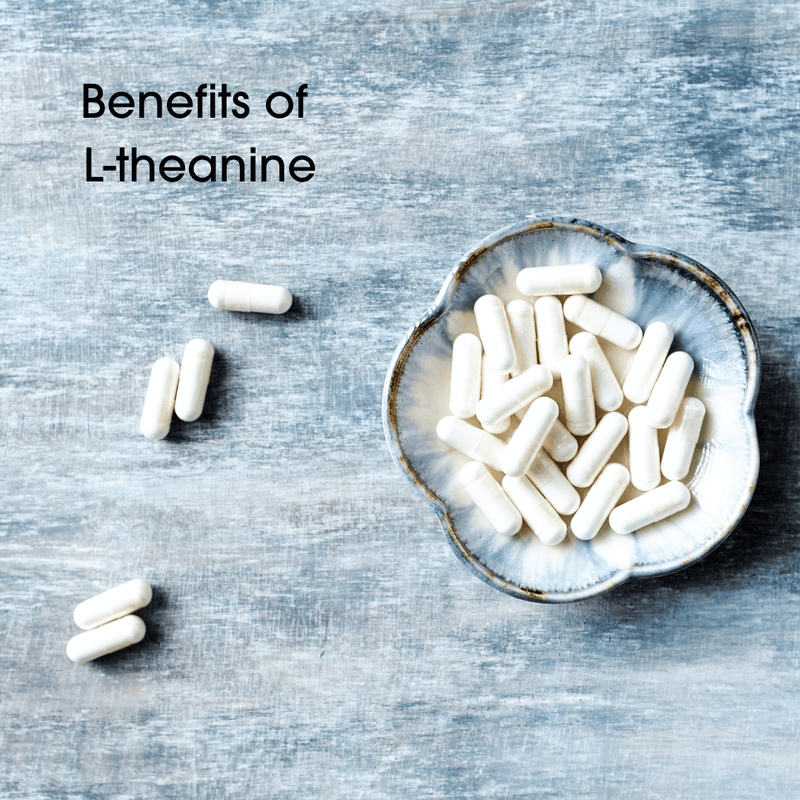 White capsule pills on grey table with words Benefits of L-theanine written on the image