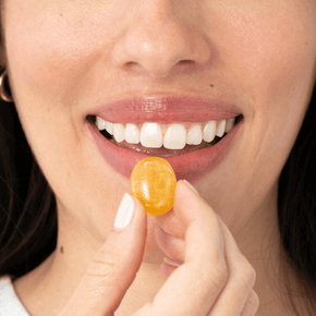 Woman holding kindroot lozenge next to mouth