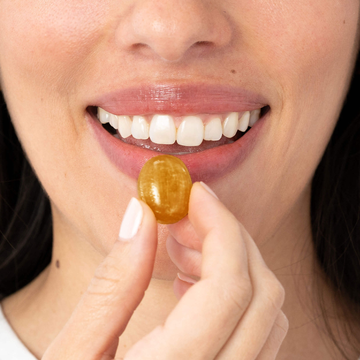 Woman holding kindroot lozenge next to mouth